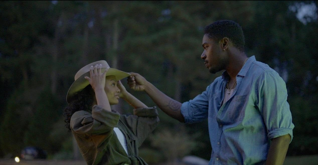 Darren placing a hat on Anissa outdoors