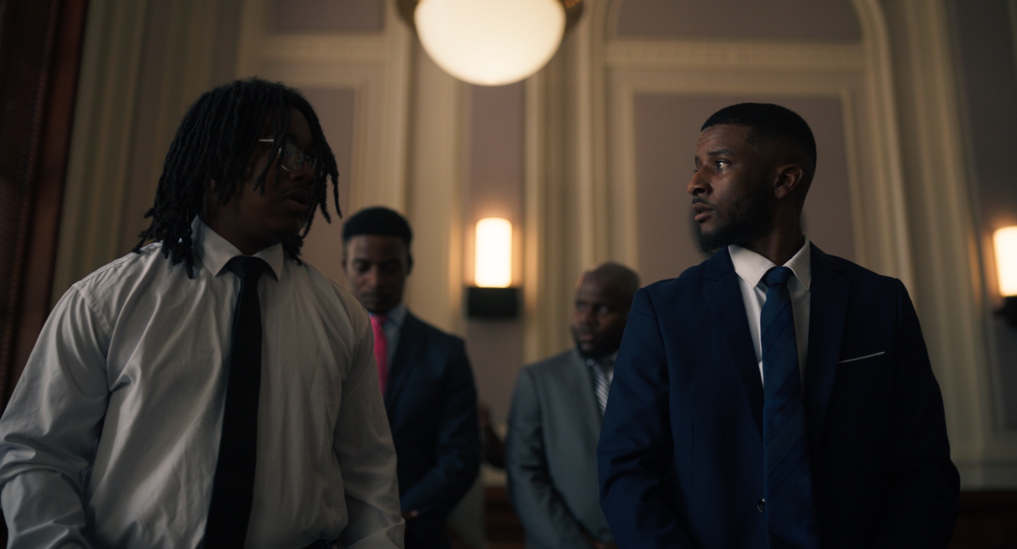 A cinematic scene with men in formal attire